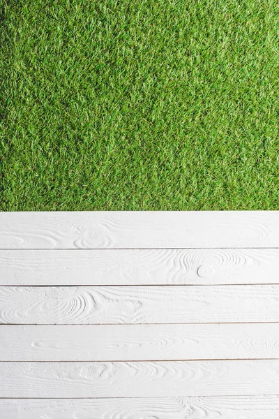 Top view of green lawn and white wooden planks background — Stock Photo