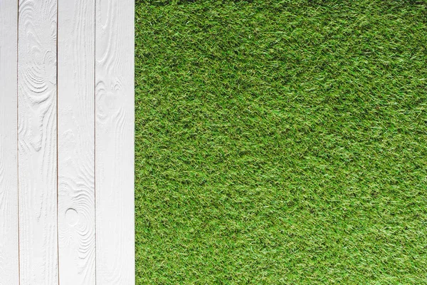 Вид сверху на зеленую лужайку и белый деревянный фон — стоковое фото