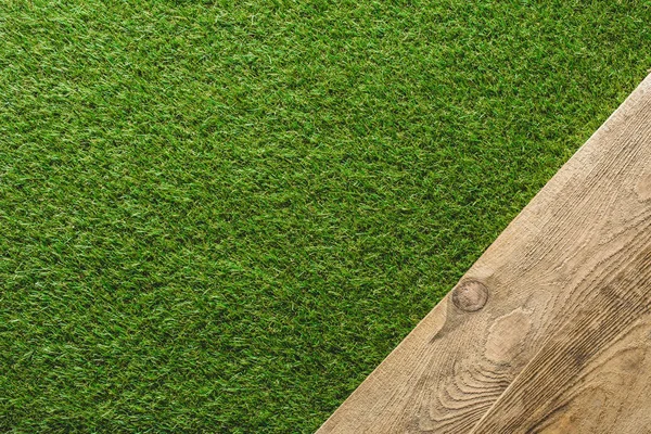 Top view of green lawn and wooden plank background — Stock Photo