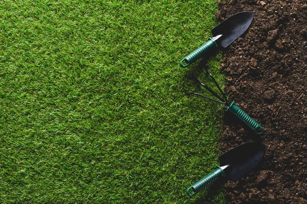Top view of grass and shovels with hand rake on soil — Stock Photo