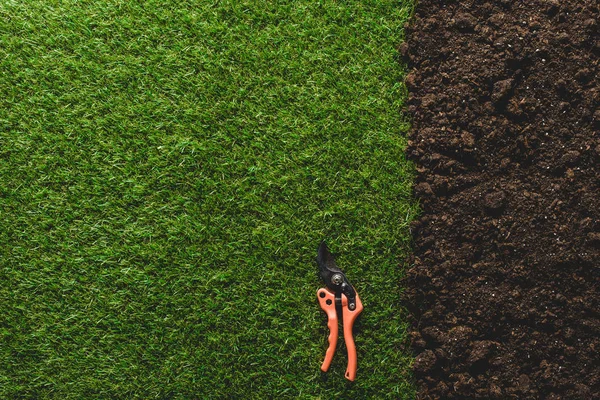 Top view of green lawn and soil with secateurs — Stock Photo