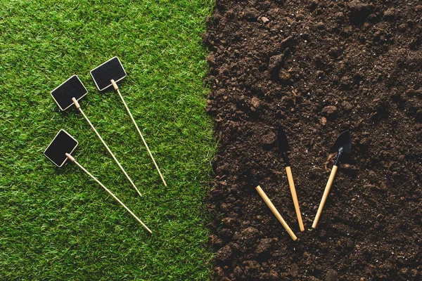 Top view of empty blackboards on grass and gardening tools on soil — Stock Photo