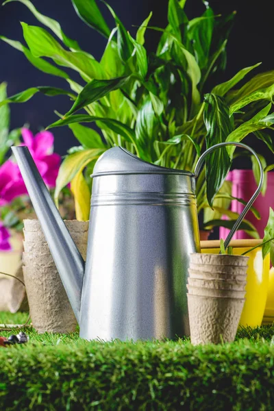 Vista close-up de regar lata e vasos de flores na grama — Fotografia de Stock