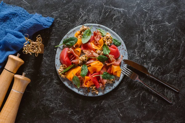 Delicious salad with mussels, vegetables and jamon on black marble surface — Stock Photo