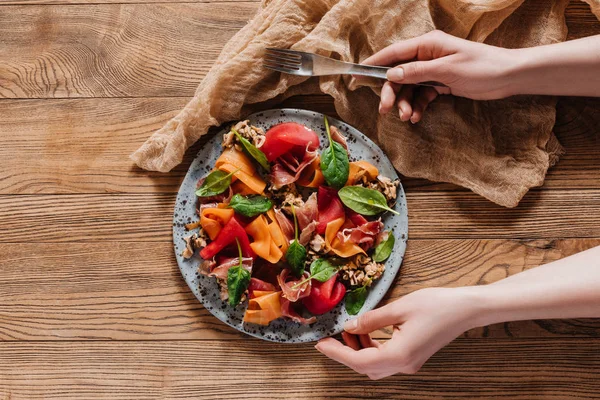 Person holding fork and plate with salad with mussels, vegetables and jamon — Stock Photo