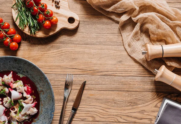 Top view of Ceviche with dorado, fork and knife, fresh tomatoes and spices on wooden table — Stock Photo