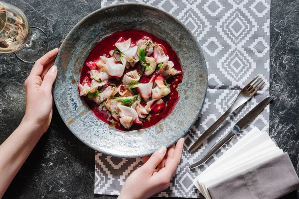 Tiro recortado de la persona sosteniendo plato con deliciosa comida con dorado - foto de stock