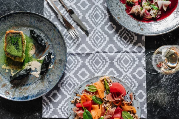 Top view of various gourmet dishes and glass of wine on marble table top — Stock Photo