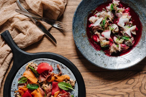 Blick von oben auf Gourmetsalat mit Muscheln und leckerem Ceviche mit Dorado auf Holztisch — Stockfoto