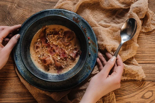 Tiro cortado de pessoa segurando colher e comer deliciosa sopa de creme com jamon — Fotografia de Stock