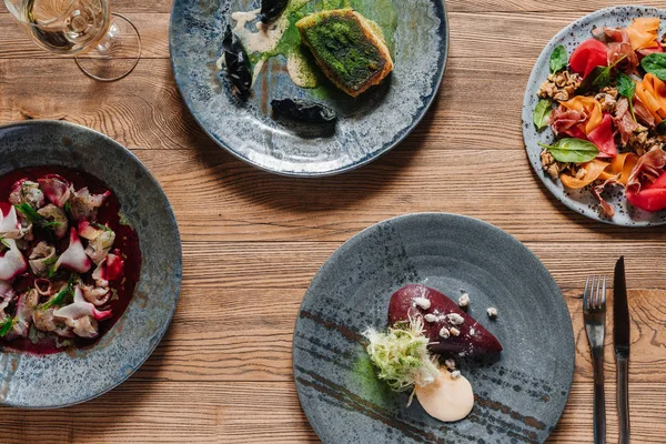 Vista superior de deliciosos platos y copa de vino en mesa de madera - foto de stock