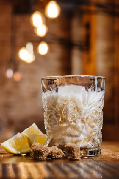 Vista de primer plano de vidrio con cóctel de alcohol crema, limón y azúcar morena en la mesa de madera - foto de stock