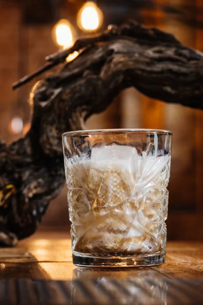 Vista de primer plano de cóctel alcohólico con crema en vidrio sobre mesa de madera - foto de stock