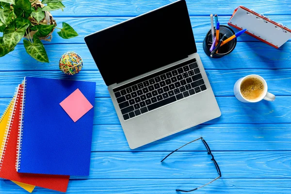 Portátil abierto y papelería en mesa de madera azul — Stock Photo