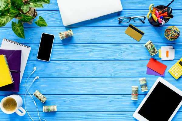 Local de trabalho com dinheiro e gadgets na mesa de madeira azul — Fotografia de Stock