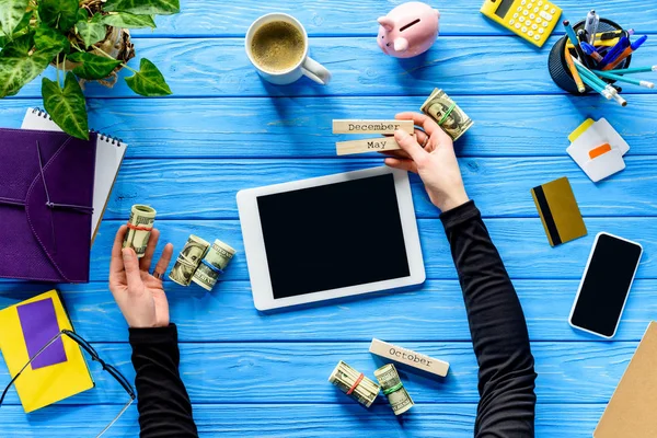 Concepto de gastos de planificación con persona de negocios con calendario y dinero en mesa de madera azul - foto de stock