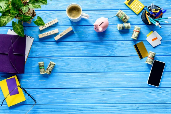 Concepto de negocio con dinero y papelería sobre mesa de madera azul - foto de stock