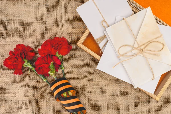 Top view of stacks of letters on photo frame and carnations wrapped by st. george ribbon — Stock Photo