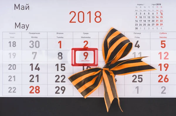 Съемка календаря крупным планом с датой 9 мая и лук, сделанный лентой Св. Георгия — стоковое фото