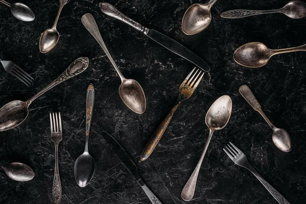Cucharas y tenedores vintage con cuchillos sobre fondo oscuro - foto de stock