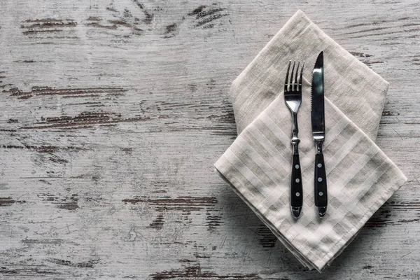 Metal fork with knife on napkin on wooden table — Stock Photo