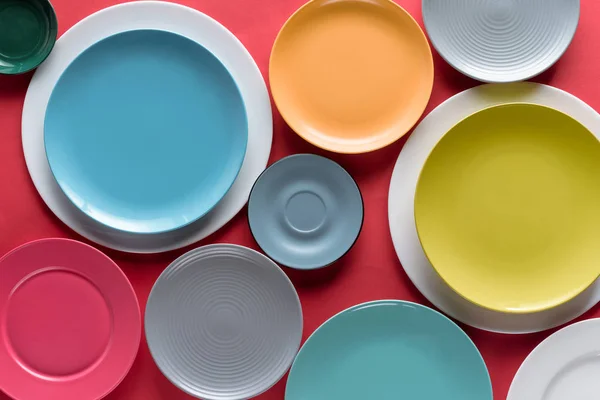 Stacks of colorful porcelain plates on red background — Stock Photo