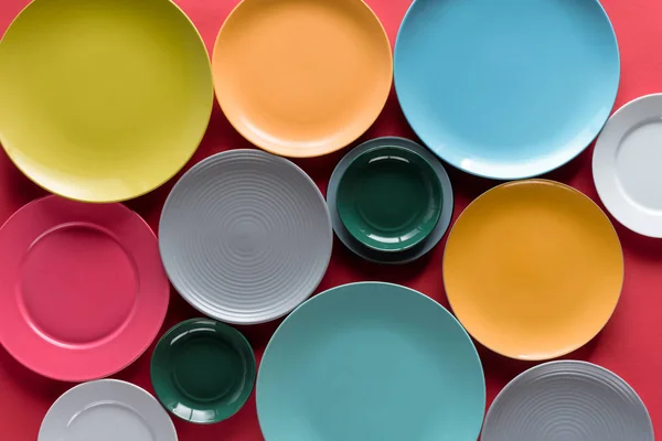 Shiny colorful kitchen ceramic plates on red background — Stock Photo