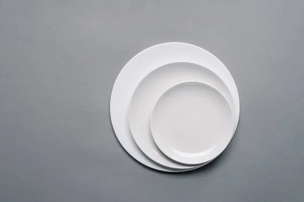 White plates of different sizes on grey background — Stock Photo