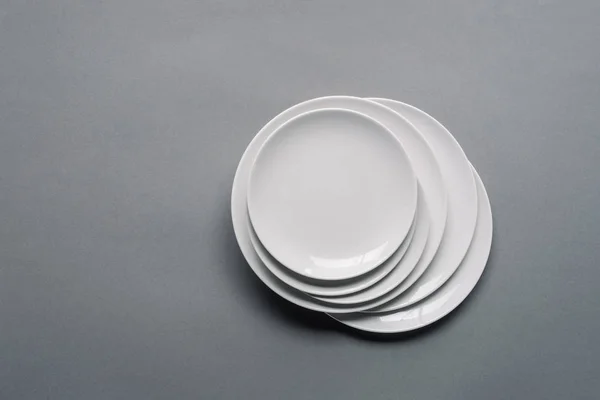 Lot de assiettes en porcelaine blanche sur fond gris — Photo de stock