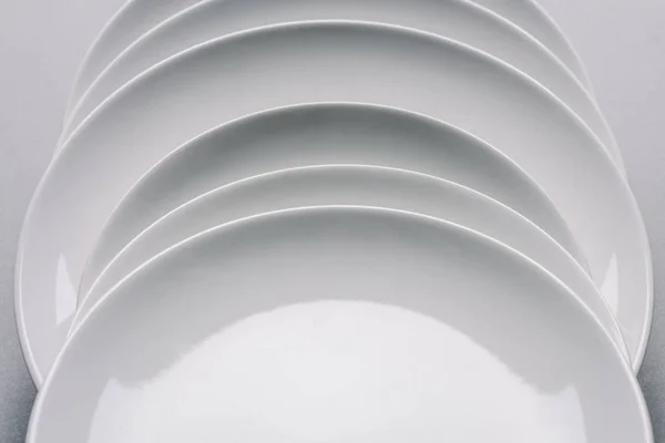 White plates in a row on white table — Stock Photo