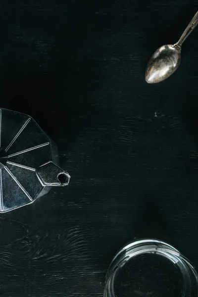 Flat lay with coffee maker, empty glass and spoon on black tabletop — Stock Photo