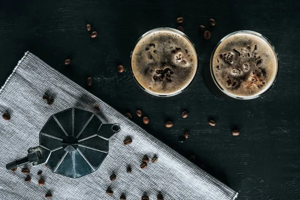 Flat lay com cafeteira e copos de café frio em mesa preta — Fotografia de Stock
