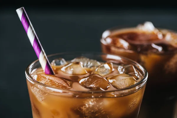 Selective focus of glass of cold iced coffee with straw on dark background — Stock Photo