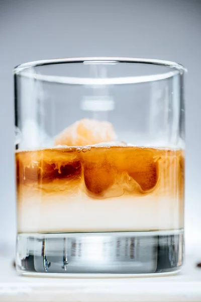 Close up view of cold iced coffee with milk in glass on grey background — Stock Photo