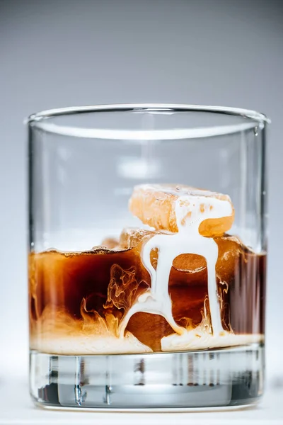 Vue rapprochée du café glacé froid avec du lait en verre sur fond gris — Photo de stock