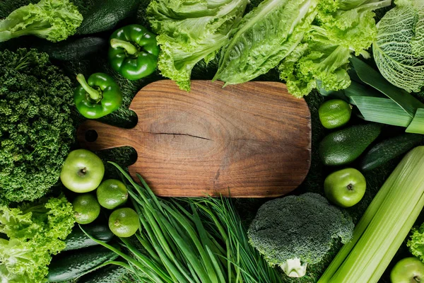 Vue du dessus de la planche à découper entre légumes verts et fruits, concept de saine alimentation — Photo de stock