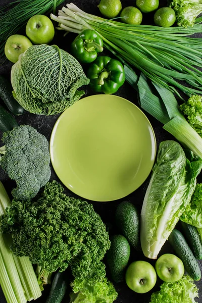 Top view of green plate between green vegetables, healthy eating concept — Stock Photo