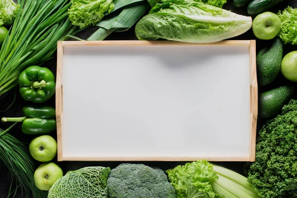 Vista superior de bandeja en blanco entre verduras verdes, concepto de alimentación saludable - foto de stock