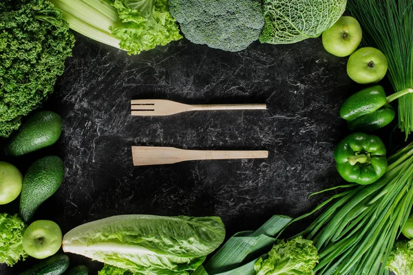 Vue du dessus de la spatule et de la fourchette en bois entre les légumes verts, concept de saine alimentation — Photo de stock