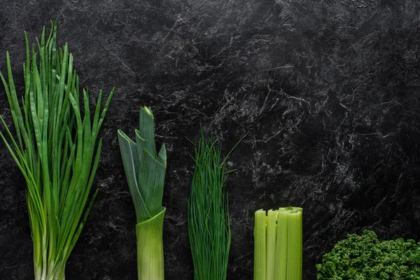 Vista superior de cebolla verde, puerro y cebollino sobre mesa de hormigón, concepto de alimentación saludable - foto de stock