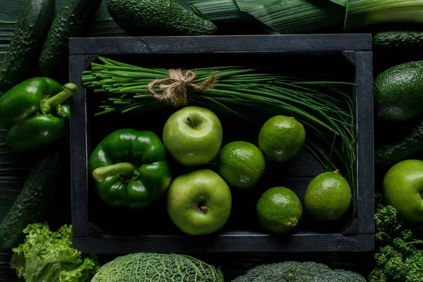 Top view of green vegetables and fruits in wooden box on table, healthy eating concept — Stock Photo