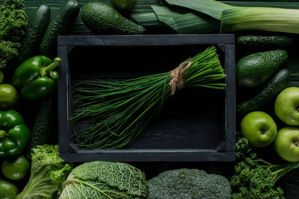 Vista superior de cebollino en caja de madera entre verduras verdes, concepto de alimentación saludable - foto de stock