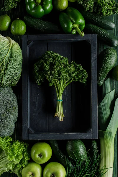 Vista superior del racimo de perejil en caja de madera entre verduras verdes, concepto de alimentación saludable - foto de stock