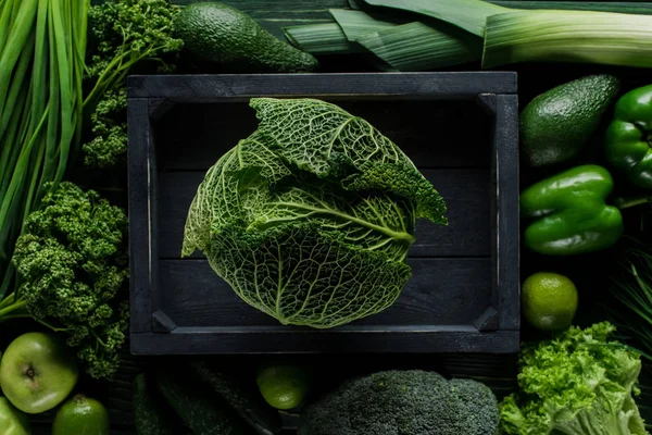 Top view of green savoy cabbage in wooden box between vegetables, healthy eating concept — Stock Photo