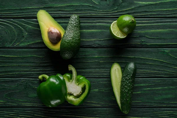 Top view of halves of cut green vegetables and fruit on wooden table, healthy eating concept — Stock Photo