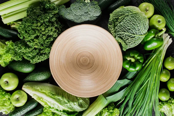 Top view of cutting board between green vegetables, healthy eating concept — Stock Photo