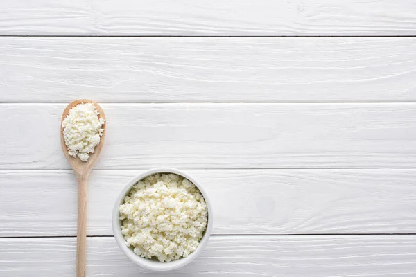 Fresh healthy cottage cheese in bowl and wooden spoon on table — Stock Photo