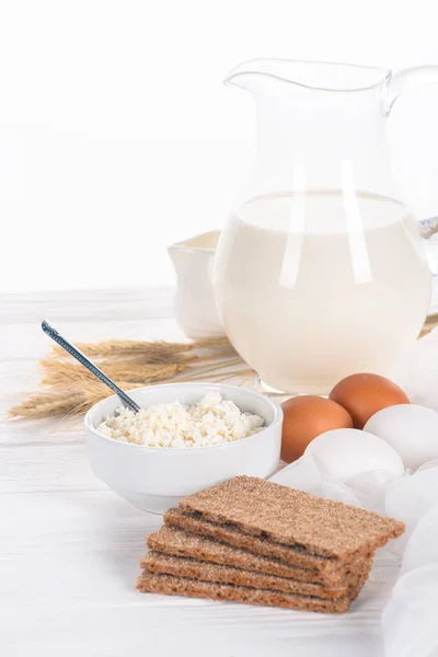 Крупный план хрустящих крекеров, яиц, молока и творога на деревянном столе — стоковое фото