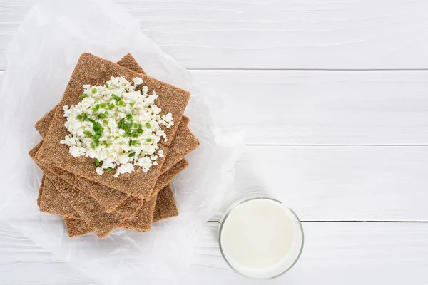 Vue du dessus du verre de lait et craquelins avec fromage cottage sur table en bois — Photo de stock