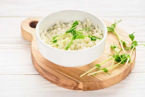 Close-up view of bowl with fresh healthy cottage cheese with sprouts on wooden board — Stock Photo